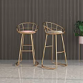 Modern Luxury Bar Stools with Golden Metal Legs and Gray Padded Seats in Contemporary Interior