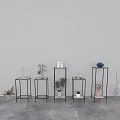 Black Metal Frame Plant Stands Displaying Various Vases and Flowers Against Gray Wall and Floor