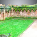Ancient Architecture Ruins with Gothic Stone Walls Covered in Moss and Internal Lawn