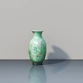 Green Ceramic Vase with Intricate Floral Patterns on Gray Table and Light Gray Wall