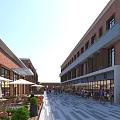 Vibrant Commercial Street With Red Brick Buildings Outdoor Seating Green Plants And People Walking