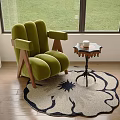 Green Upholstered Lounge Chair With Wooden Legs And Side Table On Round Floral Rug