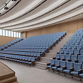 Modern Conference Room With Tiered Blue Seats Stage Red Curtain Curved Ceiling And Wooden Walls