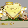 Comvita Product Display With Yellow Background Hexagon Shelves White Pillars And Flower Decorations