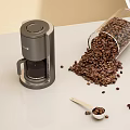 Decorative Ornament Set With Coffee Maker Glass Jar Spilled Beans Small Spoon On White Countertop