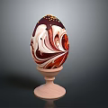 Decorated Chocolate Egg With Red And White Marble Pattern And Gold Sprinkles On Wooden Stand