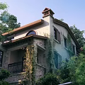 Charming Detached Villa With Brown Roof Stone Exterior And Climbing Plants Surrounded by Trees