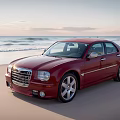 Red Sedan Parked On Scenic Sandy Beach With Ocean Waves And Sunset Sky