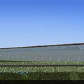 Modern Industrial Factory Building With Arched Glass Roof Under Blue Sky And Green Grass