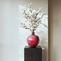 Red Vase with White Flowering Branches on Dark Square Pedestal in Soft Light and Shadow