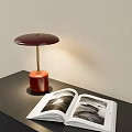 Modern Table Lamp With Red Base Golden Pole Warm Light And Open Book On Desk
