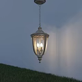 Classic Metal Outdoor Pendant Light With Glass Shade Illuminated Over Grass