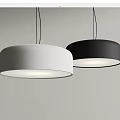Two Modern White and Black Round Pendant Lights Illuminated Against Gray Wall