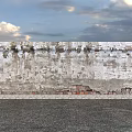 Weathered Building Exterior Wall With Peeling Surface And Exposed Red Bricks Against Sky