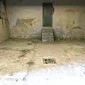 Old Unfinished Basement With Peeling Walls Green Door And Stained Floor Drain