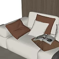 Brown And White Decorative Pillows On Beige Sofa With Open Magazine