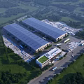 Aerial view of modern industrial factory with large metal roof surrounding greenery and parking areas