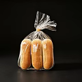 Three Fresh Bread Loaves in Transparent Plastic Bag on Black Background