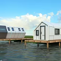 Modern Waterfront Guesthouse Buildings with Wooden Platforms Over Calm Water and Scenic Blue Sky View