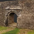 Ancient Stone Gate With Archway Design In Stone Wall And Stone Steps Near Grass Area