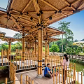Wooden Pergola Structure Over Pond With Green Trees Grass And Blue Sky