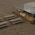 Outdoor Gathering Area With Tent Canopies Picnic Tables Storage Boxes And String Lights On Sand