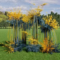 Tall Decorative Columns With Yellow Blue Flowers On Green Grass With Trees And Sky