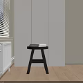 Black Round Side Table with Three Legs and Books on Wooden Floor Near White Cabinets