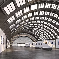 Modern Open Exhibition Hall with Arched Glass Roof White Walls and Displayed Artworks