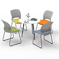 Round White Table with Four Colored Chairs Metal Legs Small Plant and Book