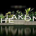 Floral Installation Featuring White 3D Letters Green Plants Yellow Flowers And Water Reflection