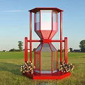Red Hourglass Shaped Structure As Photo Spot With Flowers In Grassland Under Sky