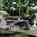 Natural Rockery Stones In Garden Landscape With Lush Green Plants And Tall Trees