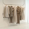 Clothes with Various Styles Hanging on Metal Rack Neutral Beige Brown White Wall Light Floor