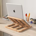 Wooden Laptop Stand On Light Desk With Green Mug Colored Pencils Figurines And Charging Phone
