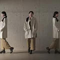 Women In Beige Coats Brown Pants And Black Shoes Against Concrete Wall