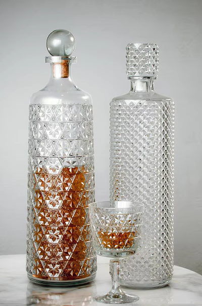 Two Elegant Transparent Patterned Wine Bottles With Brown Liquid And Small Glass Cup 3d model