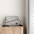 Gray Checkered Crossbody Bag With Black Strap Zipper On Wooden Cabinet By Window Blinds