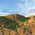 Garden Landscape Featuring Rolling Hills Green Grass And Rocky Terrain Under Blue Sky