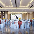 Elegant Banquet Hall with White Chairs Pink Bows Red Tables Crystal Chandeliers and Wedding Screen