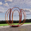 Outdoor Sculptural Art Installation With Red Orange Circular Rings Against Blue Sky