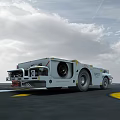 White Utility Vehicle With Large Wheels And Equipment Driving On Open Ground Under Cloudy Sky