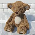 Plush Brown Teddy Bear Sitting On Bed With Striped Sheet And White Tufted Headboard