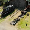 Steam Locomotive In Railway Yard With Old Warehouse And Equipment
