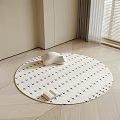 Round Rug with Black Cross Patterns White Cushion and Open Book on Light Wooden Floor