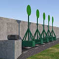 Green Sports Equipment With Circular Targets On Stands Along Gray Wall And Grass Gravel Ground