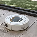 Robotic Vacuum Cleaner Cleaning Wooden Floor Near Window With Green Grass