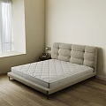 Double Bed With Light Beige Upholstered Headboard And Quilted Mattress Near Nightstand With Table Lamp