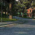 Garden Landscape with Lush Trees Green Grass Lamp Posts Red Brick Building and Curved Path