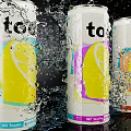 Three Colorful Too Drink Cans With Lemon Design Splashing Water And Blue Light